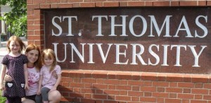 Employ-Ability participant Tara with her two kids in front of the Saint Thomas University sign