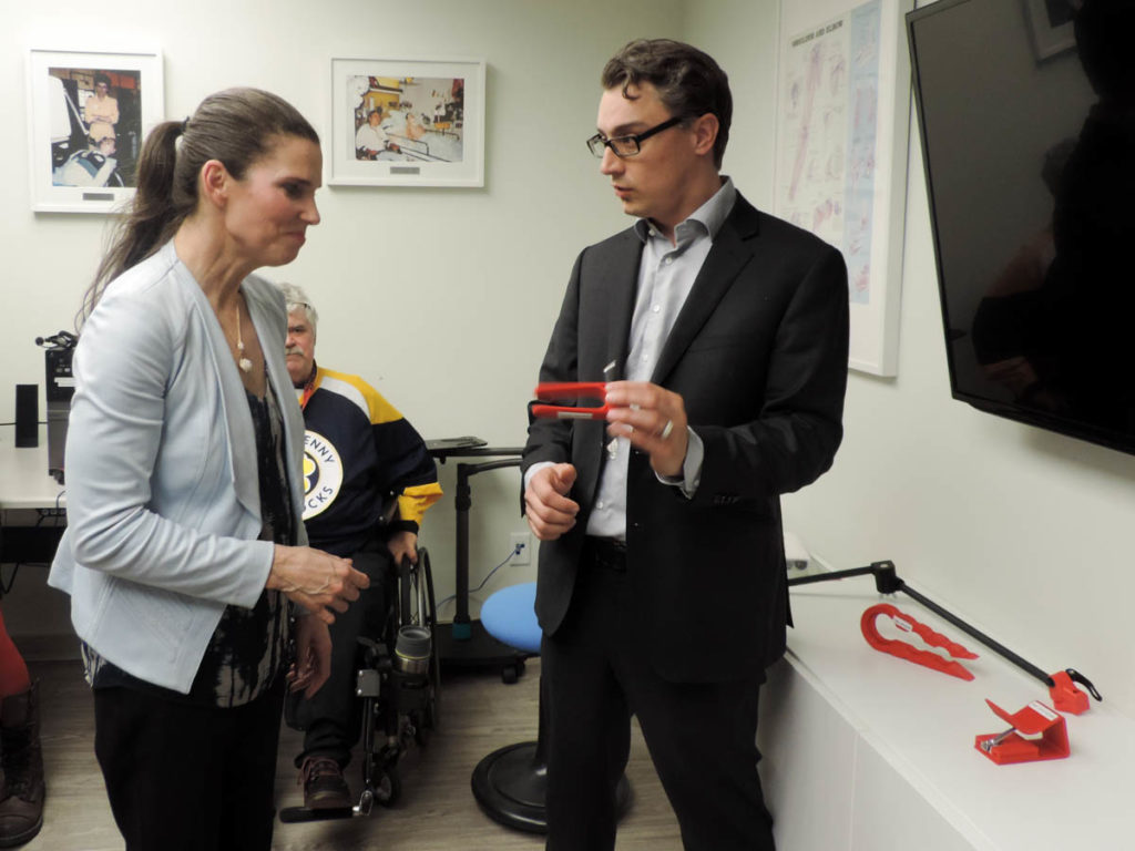 Chad Leaman, Director of Innovation, shows the Minister a pen holder that slips on the palm