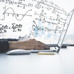 stock image of hands on a laptop with equations coming out of the screen