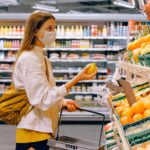 stock image of woman in supermarket holding up fruit