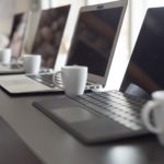 A number of laptops placed in a row on a desk