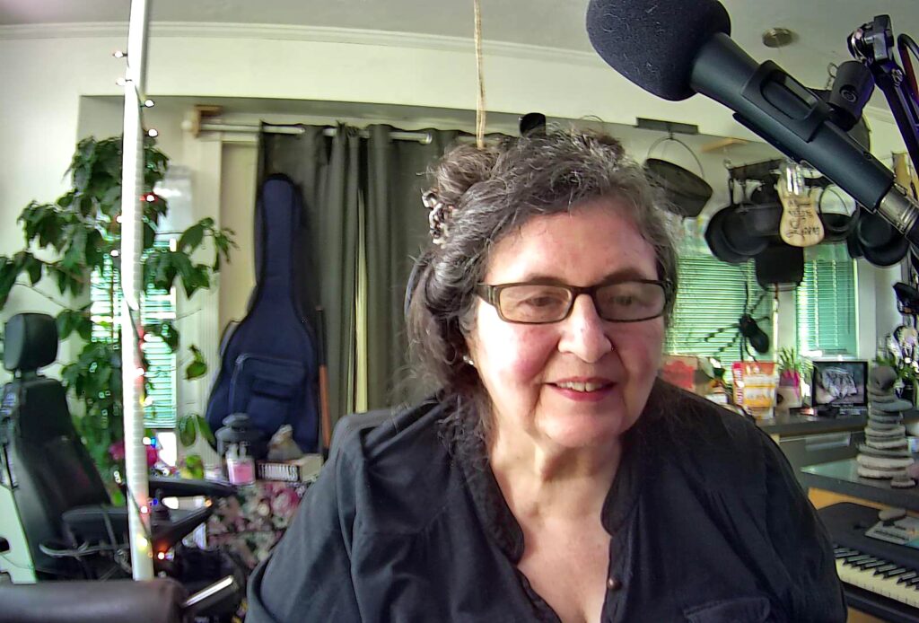 Jaycee at home, smiling. Above her is a mic.