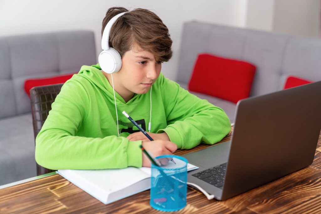 a child using a laptop, wearing headphones