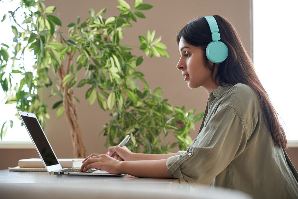 Student wearing blue headphones while using a laptop