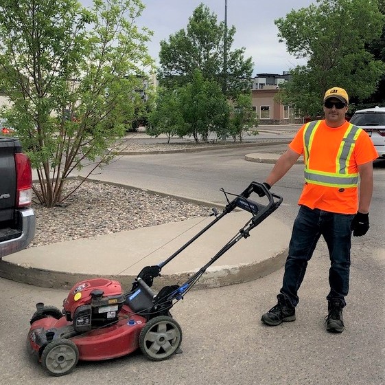 Jason working outdoors, holding a lawn mower