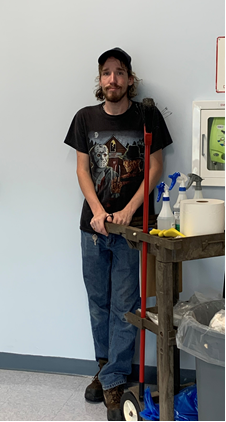 Luke at work. He is leaning against the wall, with cleaning equipment next to him