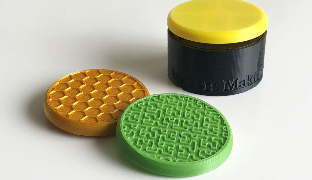 A gold honeycomb textured and green maze textured switch tops. In the background is a yellow round flexure switch