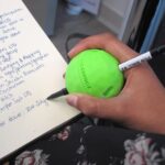 A user using the 3D Printed Pen Ball Holder to write on a piece of paper with ease
