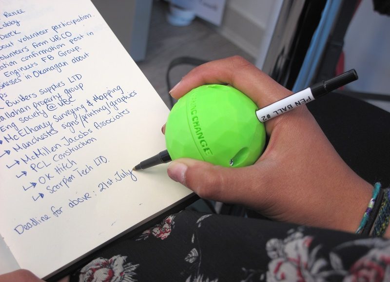 A user using the 3D Printed Pen Ball Holder to write on a piece of paper with ease
