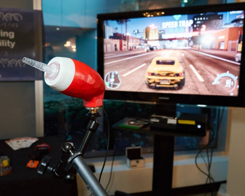 A LipSync is mounted in front of a TV which is a displaying a racing video game