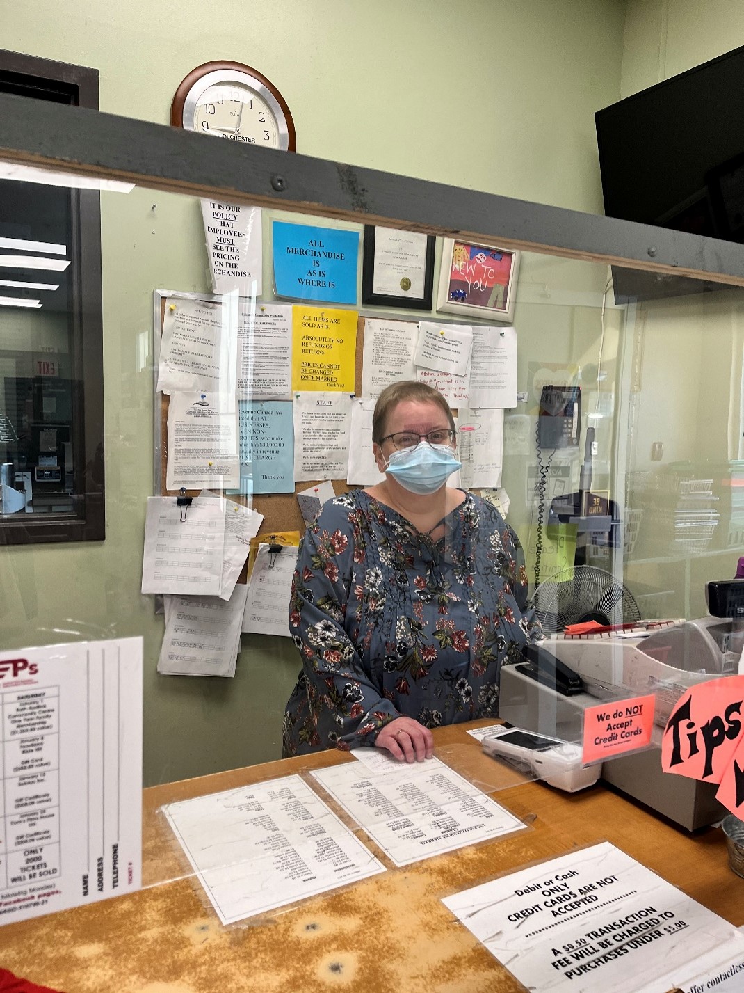 Working Together participant Patty working behind the counter, wearing a mask and behind plexiglass