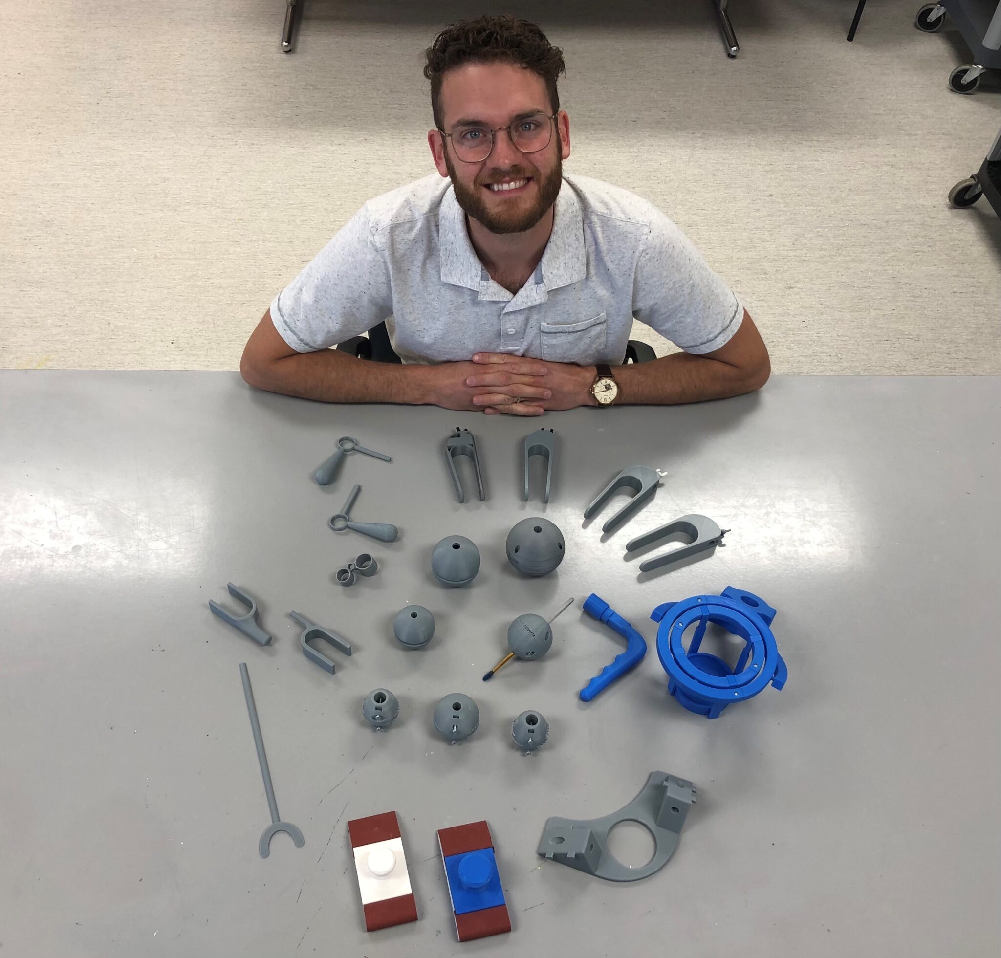 Lucas showing off the devices they 3D printed, including pen balls and palm pen holders