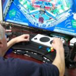 A person gaming with the Xbox Adaptive Gaming controller in front of a TV