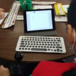 a young boy using a keyguard to use a keyboard for his tablet