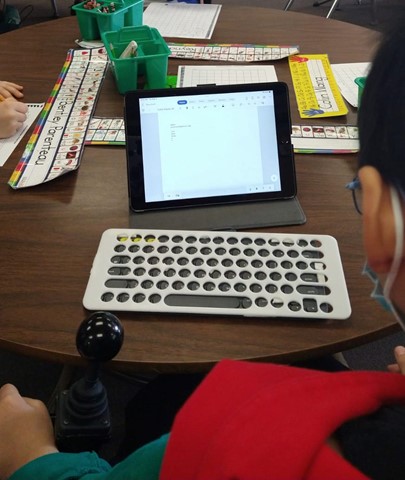 a young boy using a keyguard to use a keyboard for his tablet