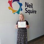 Chelsea holding a certificate for Ergonomics from the University of Fredericton School of Occupational Health and Safety
