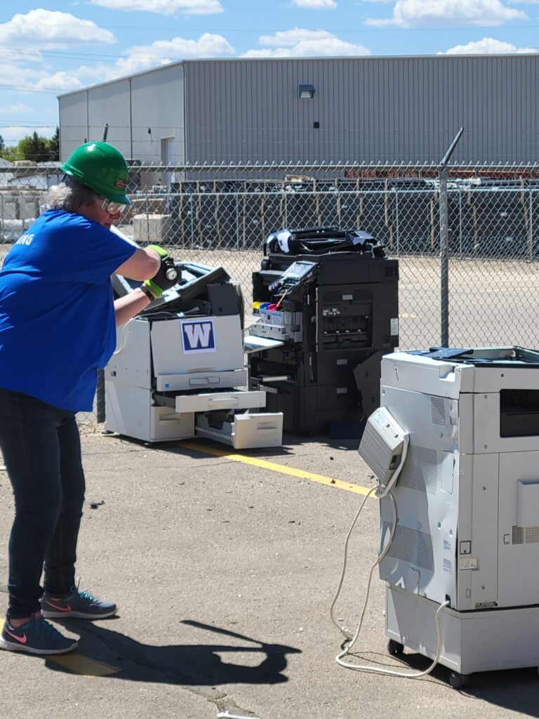 Colleen smashing a copier with a baseball bat