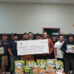 the volunteers showing off their adapted toys and a cheque to Neil Squire for $2,670