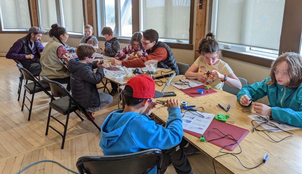 A group of young makers building switches at a long table