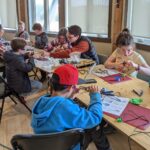 A group of young makers building switches at a long table