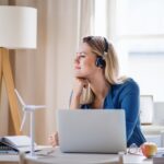 a woman wearing a headset while using a laptop