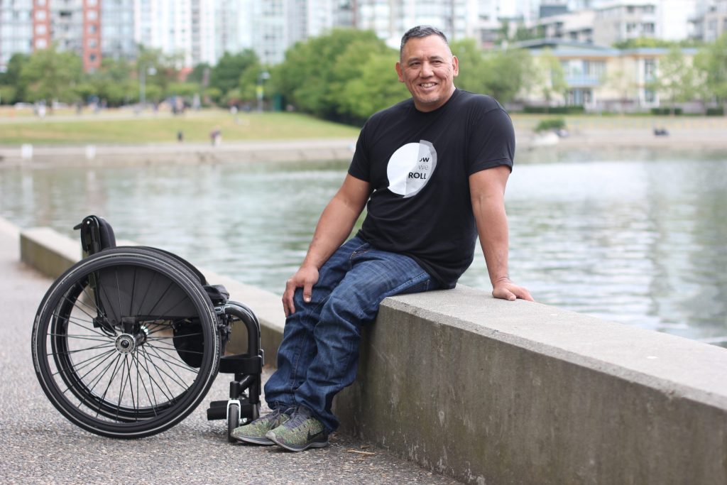 Richard sitting on the seawall next to his wheelchair