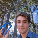MMC intern Taz showing off the re-designed Bottle Opener while standing in front of some trees outside