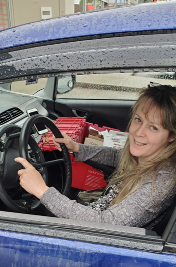 WorkBC Assistive Technology Services participant Robyn holding the steering wheel in her car with a delivery in her passenger seat