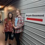 Working Together participant Jacob and his supervisor Bessie in front of a sign for the Bargain Basement