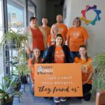 Neil Squire Regina staff wearing orange shirts and a sign that says, 