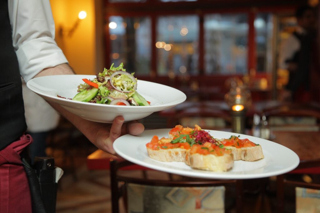 a waiter holds two plates with food on them