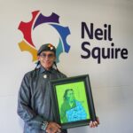 Computer Comfort participant Ron holds one of his paintings, a portrait of a man with the name, 