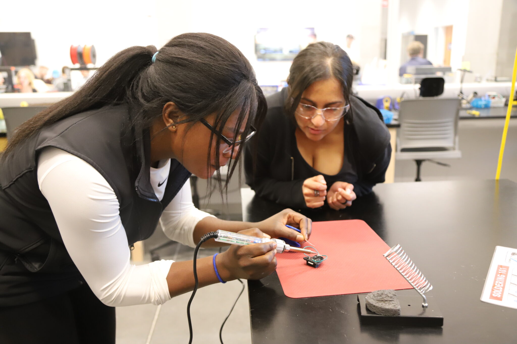 two students working together on soldering a toy