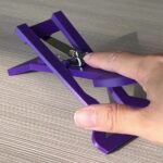 A finger on the purple 3d printed nail clipper