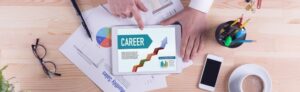 a hand pointing to the word, "career," typed on a tablet on a messy desk with multiple documents scattered