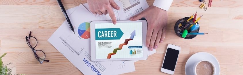 a hand pointing to the word, "career," typed on a tablet on a messy desk with multiple documents scattered
