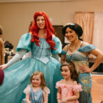 Two princess performers posing with two girls dressed as princesses