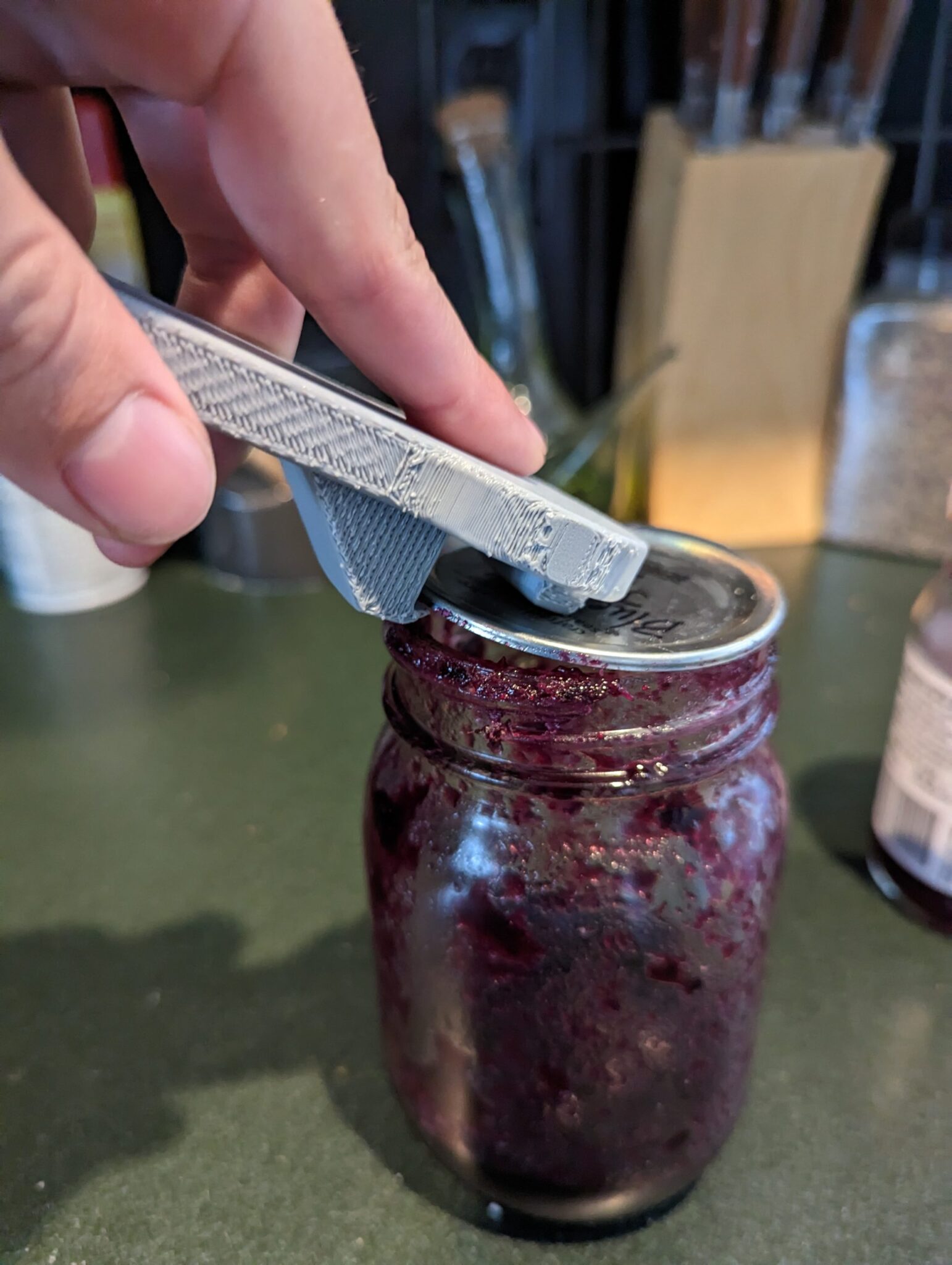 Picture of jar lid opener being used to break seal on mason jam jar.