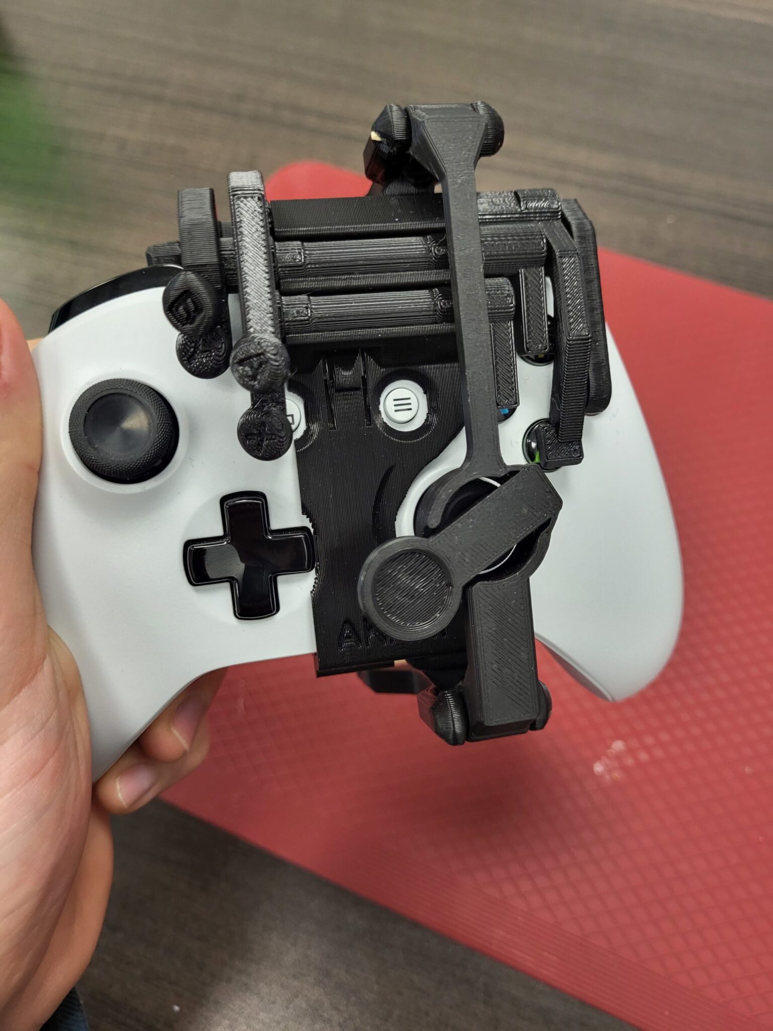 A photo showing a black, 3D printed left-handed controller mod on a white Xbox One controller.