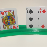 Green 3D printed device holding various playing cards