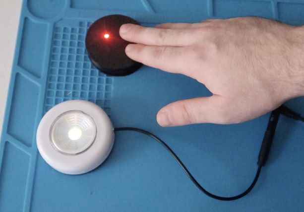 A hand activating a Touch Switch turning on a small while light.
