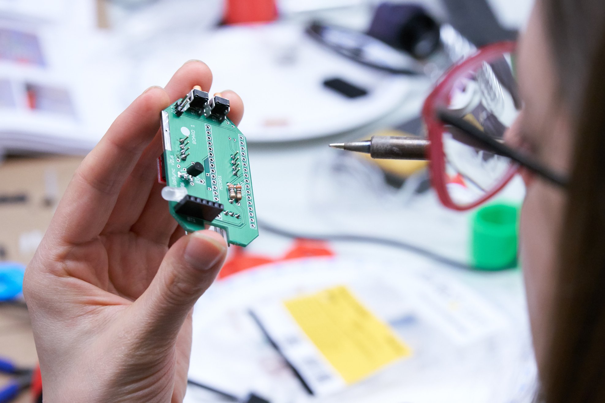 A person holds a soldering iron to a circuit board.
