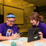 A child and a clinician use assistive technology.