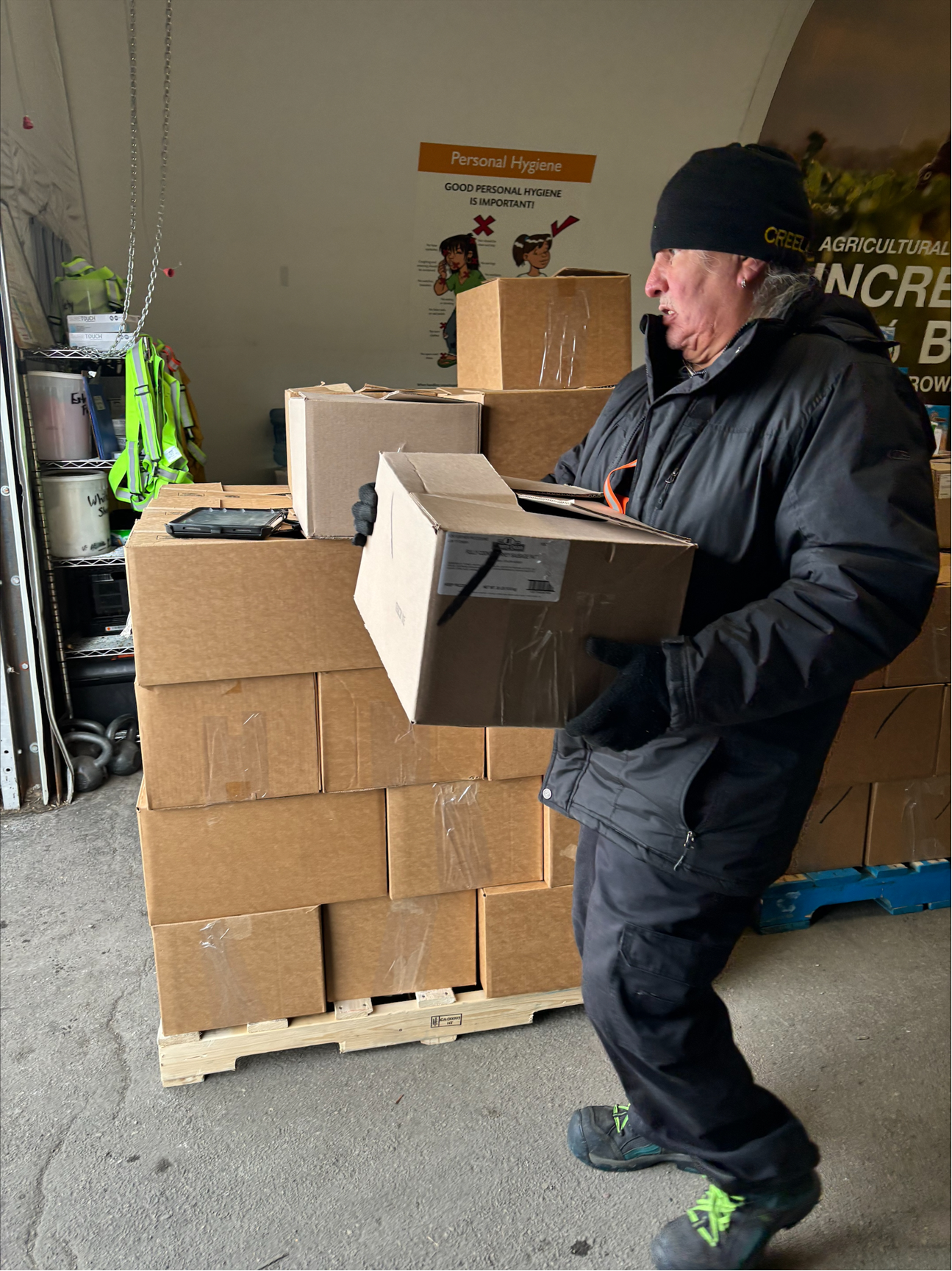 Daryn at work in a warehouse, carrying a box.