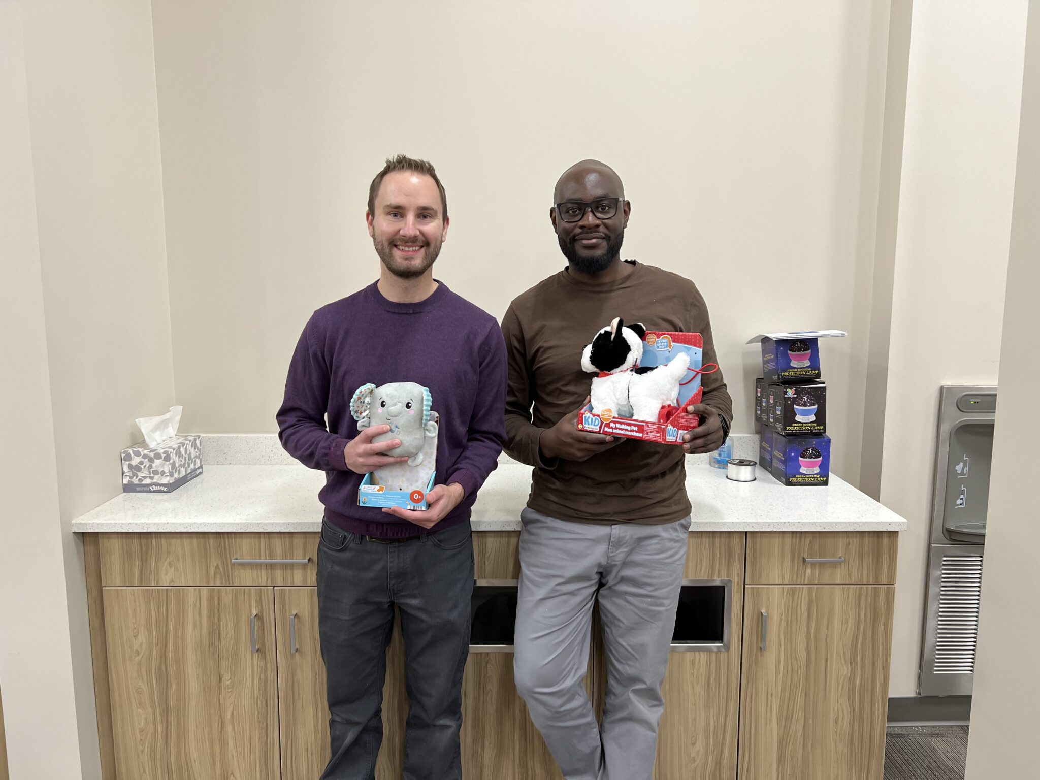 Two SaskPower employees hold up the toys they adapted.