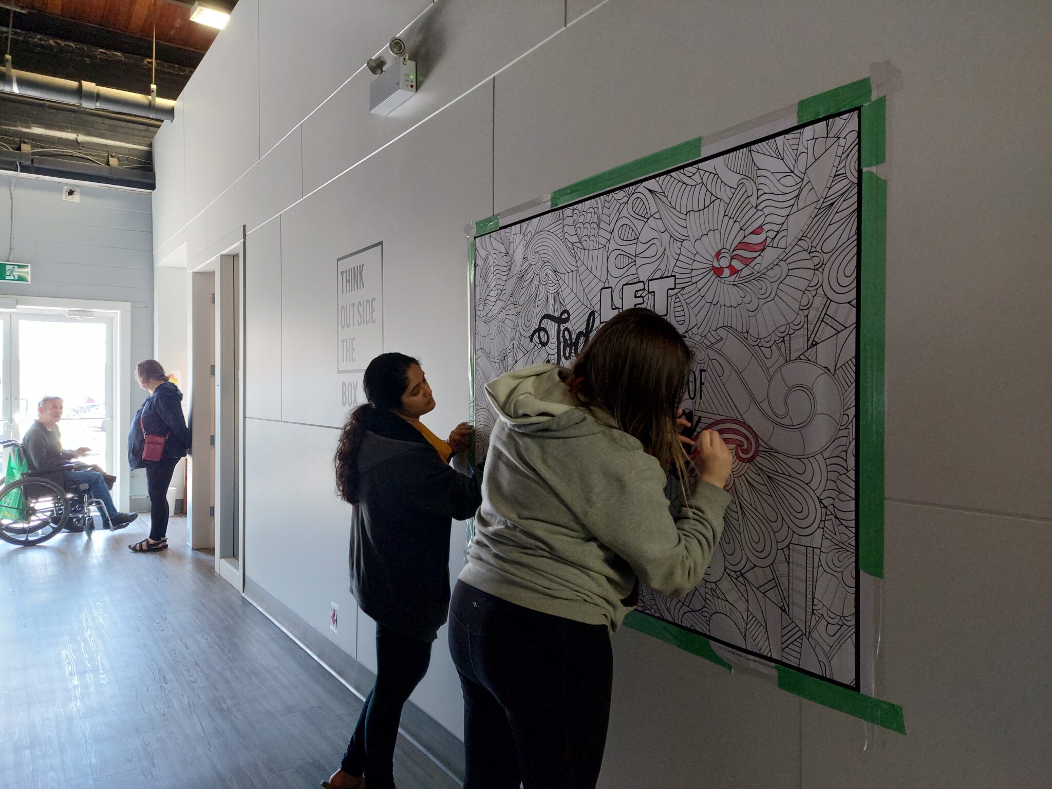 Two clients drawing on a colouring poster.