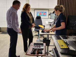 Occupational therapist Zorana Ciric demonstrates assistive technology to Wayne Ackerman and Elsa Chu Del Aguila.