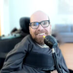 Ean in his wheelchair smiling with the new LipSync.