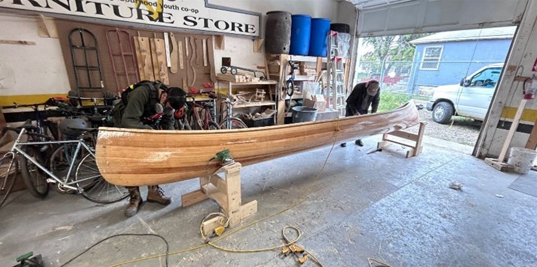 Jeremiah and a co-worker work on a canoe.