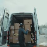 A person unloads boxes from a van.